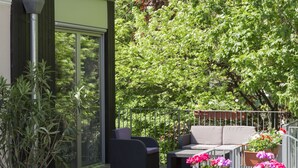 A patio area with outdoor furniture, potted plants, and a view of a lush green tree. - Höldrichsmühle (Hinterbruhl)