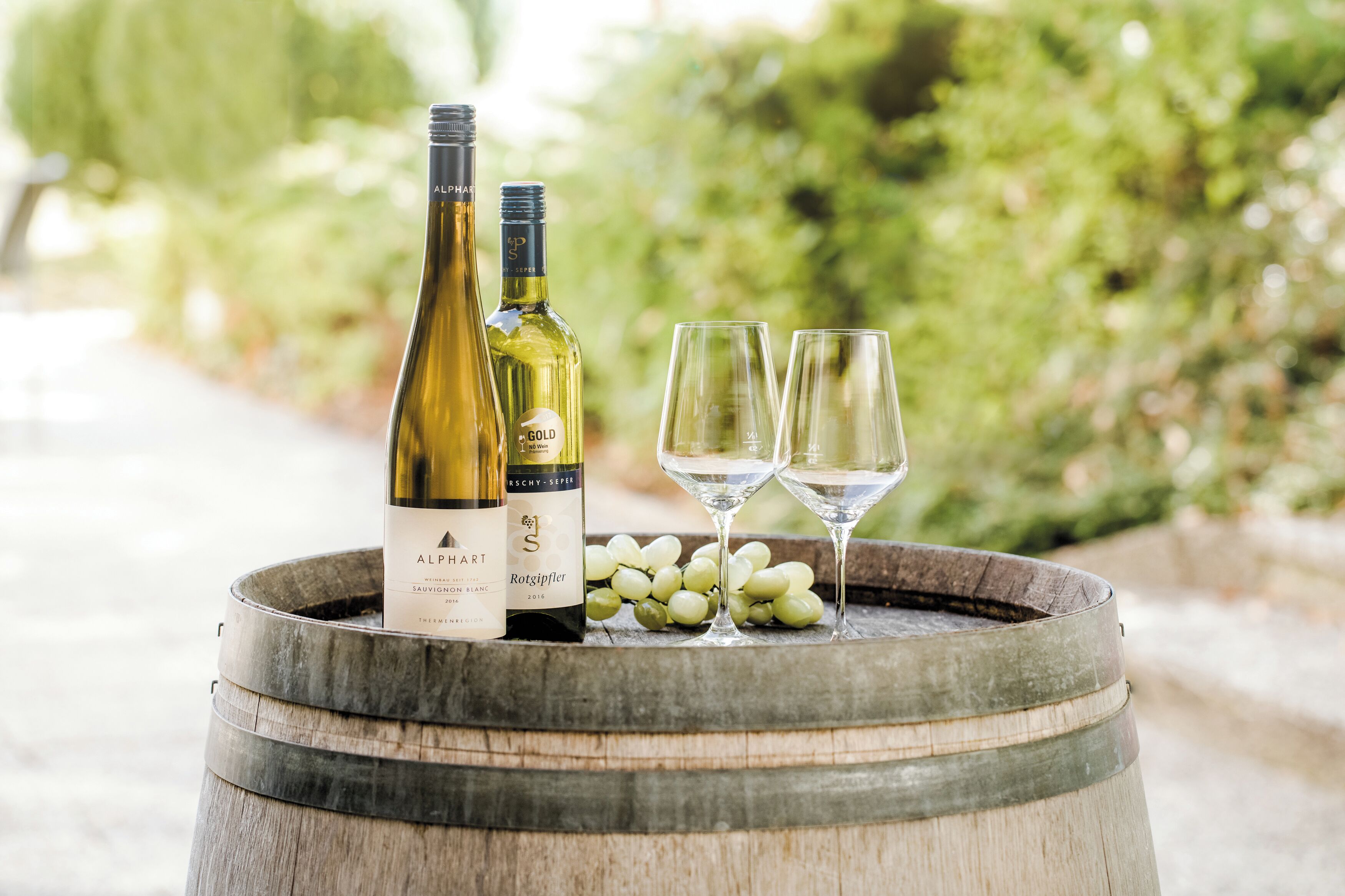 Two wine bottles and two glasses on a wooden barrel.