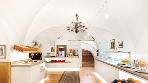 A modern kitchen with a central island, a chandelier, and a staircase leading to an upper level. - Höldrichsmühle (Hinterbruhl)