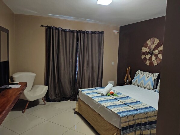 Habitación de hotel con cama, escritorio, silla y un gran elemento decorativo en la pared.