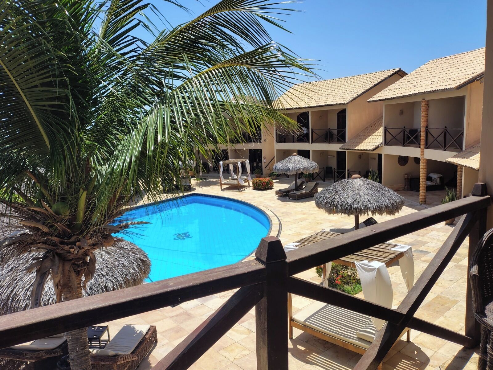 A pool area with a clear blue pool, lounge chairs, and umbrellas.