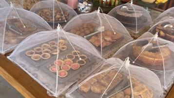 A buffet with various covered food items, including cookies and cakes, and a fruit display with tropical fruits.