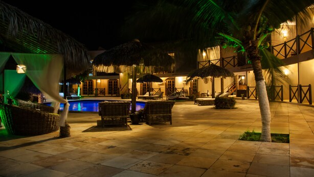 A nighttime resort with a pool, lounge chairs, and thatched umbrellas. - Pousada Aruanã (Aracati)