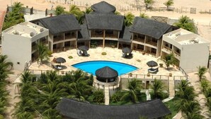 A resort with a central pool, multiple thatched-roof structures, and palm trees. - Pousada Aruanã (Aracati)