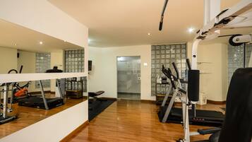 A home gym with exercise equipment, a treadmill, and a mirrored wall.