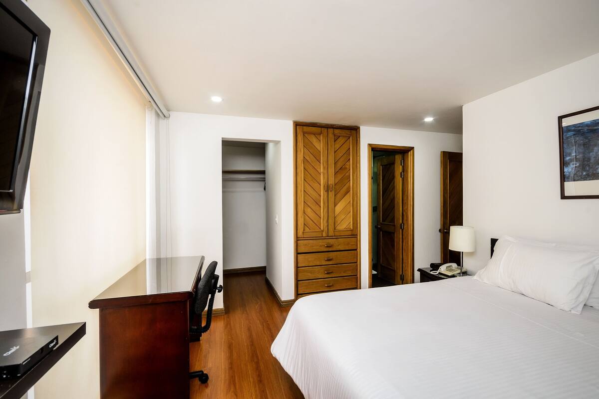 Ein Hotelzimmer mit Bett, Schreibtisch, Kleiderschrank und Fernseher.