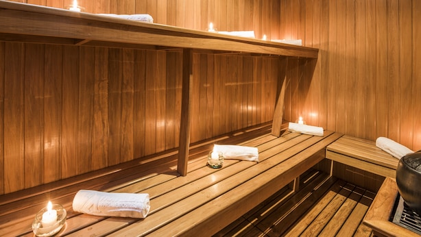 Puisesta laudelavasta, kynttilöistä ja pyyhkeistä varustettu sauna.