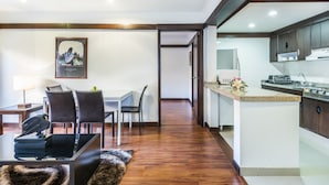 A modern kitchen with dark wooden cabinets, a granite countertop, and a built-in microwave. - Travelers Suites Condominio Plenitud  (Bogotá)