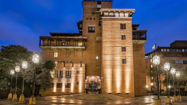 A large, multi-story building with a prominent central tower, multiple balconies, and a well-lit entrance area. - Travelers Suites Condominio Plenitud  (Bogotá)