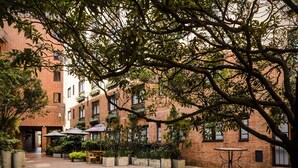 A courtyard with brick buildings, outdoor seating, and potted plants. - Travelers Suites Condominio Plenitud  (Bogotá)