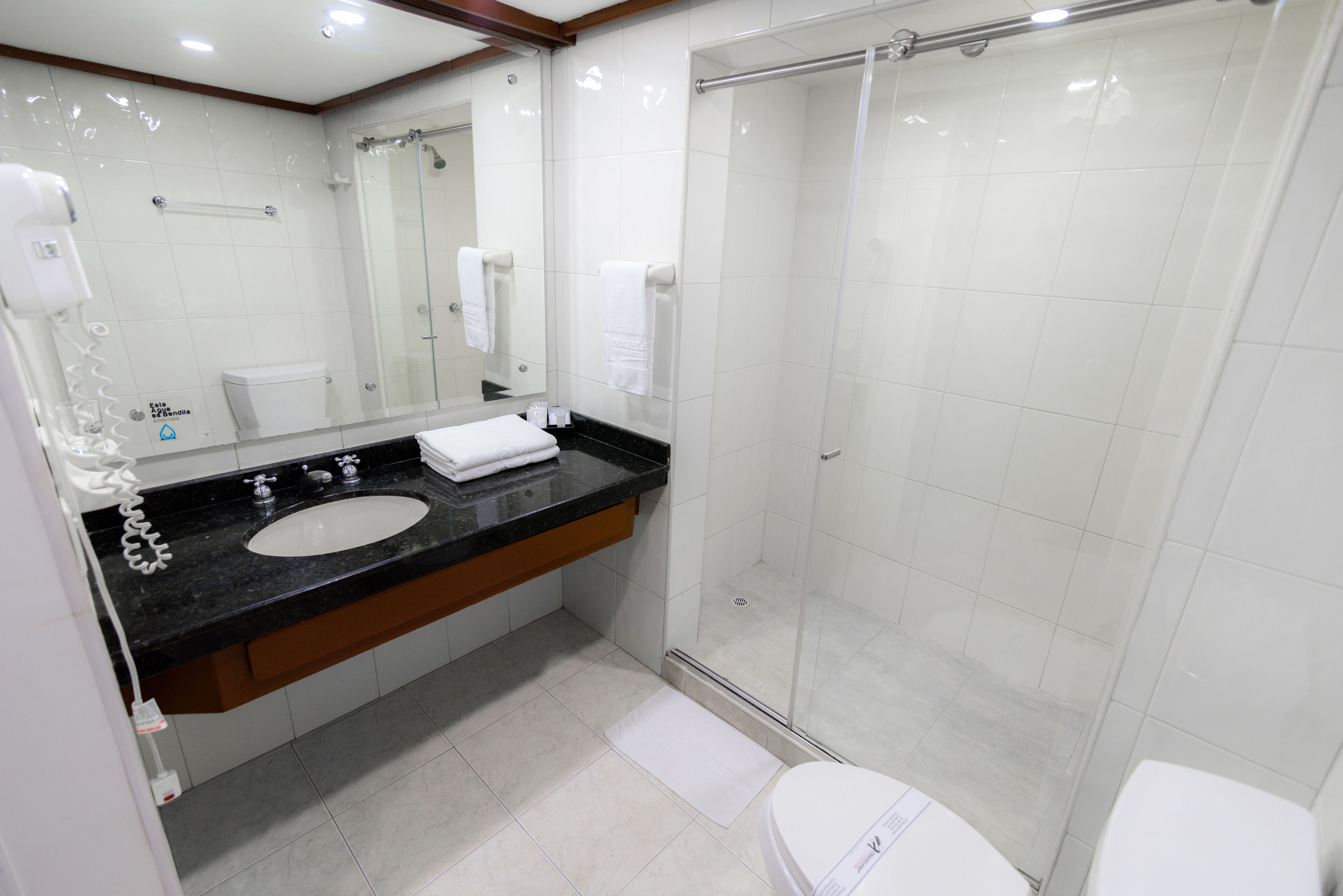 A modern bathroom with a black countertop sink, a glass shower enclosure, and a white toilet.