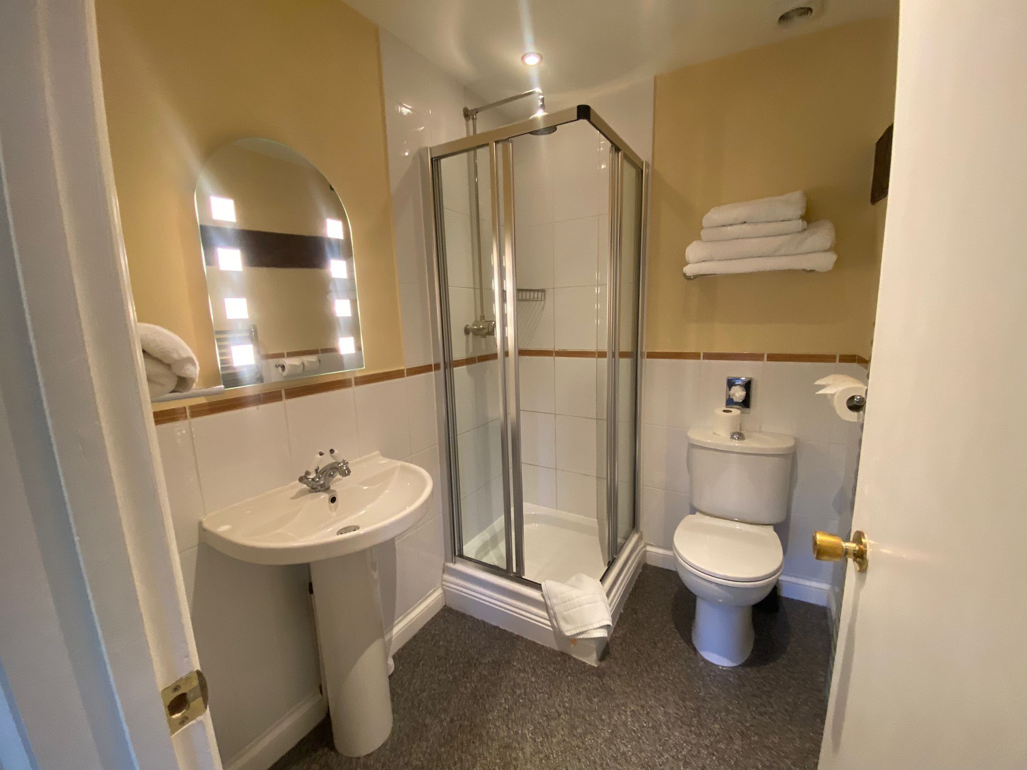 A bathroom with a glass-enclosed shower, a sink, and a toilet.