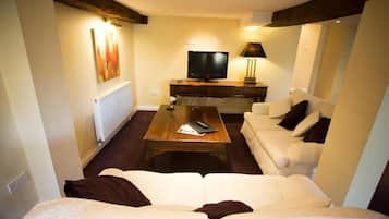 A living room with a white sofa, a wooden coffee table, a television, and a lamp.