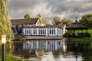 A riverside building with a gazebo, a pond with ducks, and a stone wall. - Hornsbury Mill (Chard)