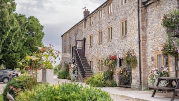 A stone building with a reception area, a staircase, and flower arrangements.