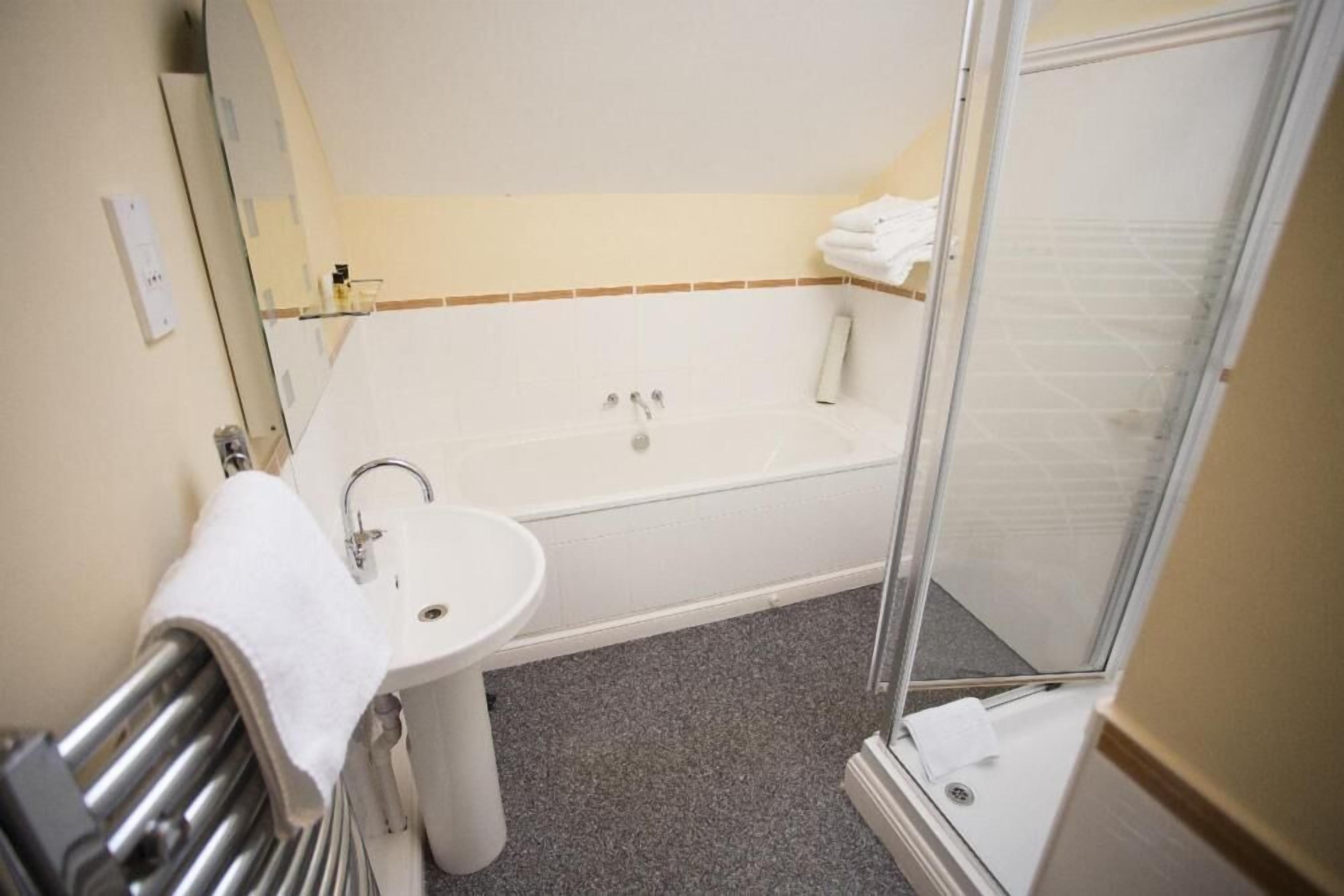 Un baño con bañera, lavamanos y cabina de ducha de vidrio.
