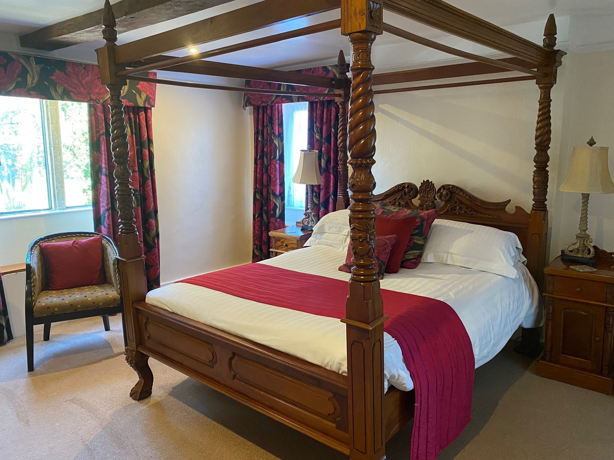 Un lit à baldaquin avec un cadre en bois, une couvre-lit rouge et des coussins assortis.