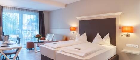 Une chambre d’hôtel avec deux lits, un coin repas et une vue sur l’extérieur.