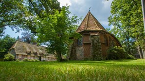 A church with a conical roof and a brick building with a stone facade. - Flair Hotel Rieckmann (Bispingen)
