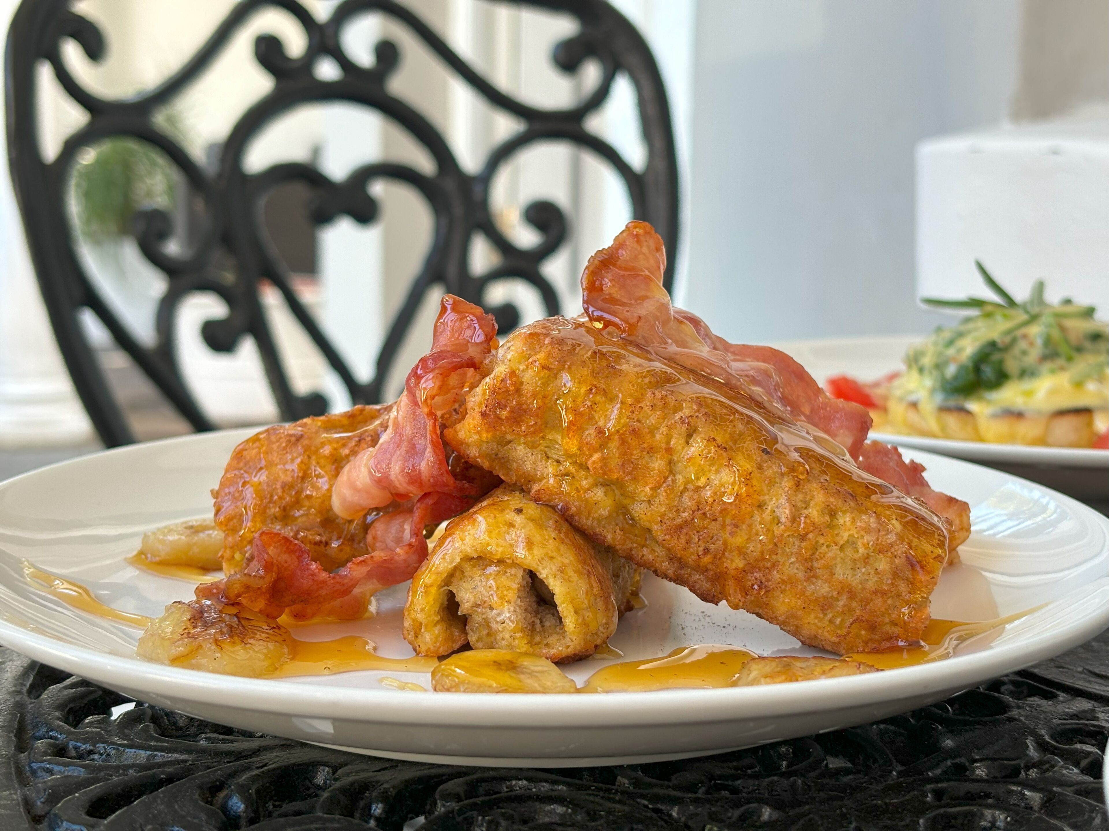 A plate of food with bacon-wrapped items and a side dish.