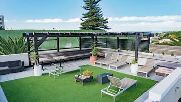 Eine Außenpatio mit einer Pergola, Sitzbereichen und Blick auf die Stadt.