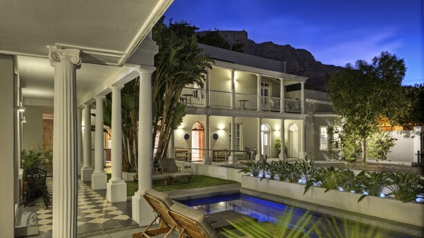 A two-story building with a pool, columns, and outdoor seating.