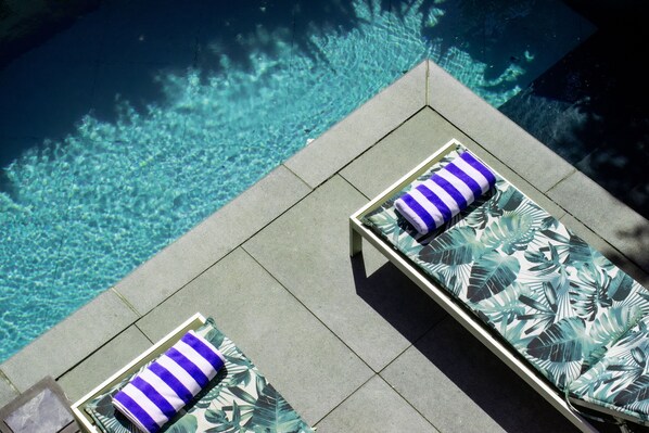 A rooftop pool area with two sun loungers, each with a striped pillow. - The Three Boutique Hotel (Cape Town)