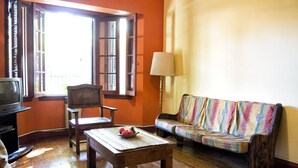 Una sala de estar con una mesa de madera, un sofá, una silla y un televisor.