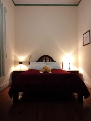 Un dormitorio con una cama, dos lámparas de noche y un cabecero de madera.