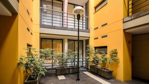 A multi-story building with yellow walls, a balcony, and potted plants. - Travelers Suites Obelisco Apartamentos (Bogotá)