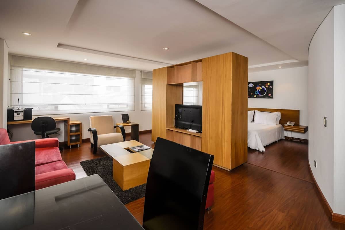 Une chambre d’hôtel moderne avec un bureau en bois, une télévision, un lit et un canapé.