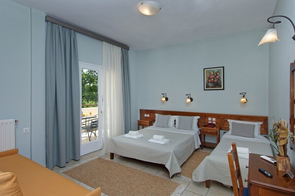A hotel room with two beds, a sofa, a dining table, and a view of the outdoors. - Hotel Katia (South Pelion)
