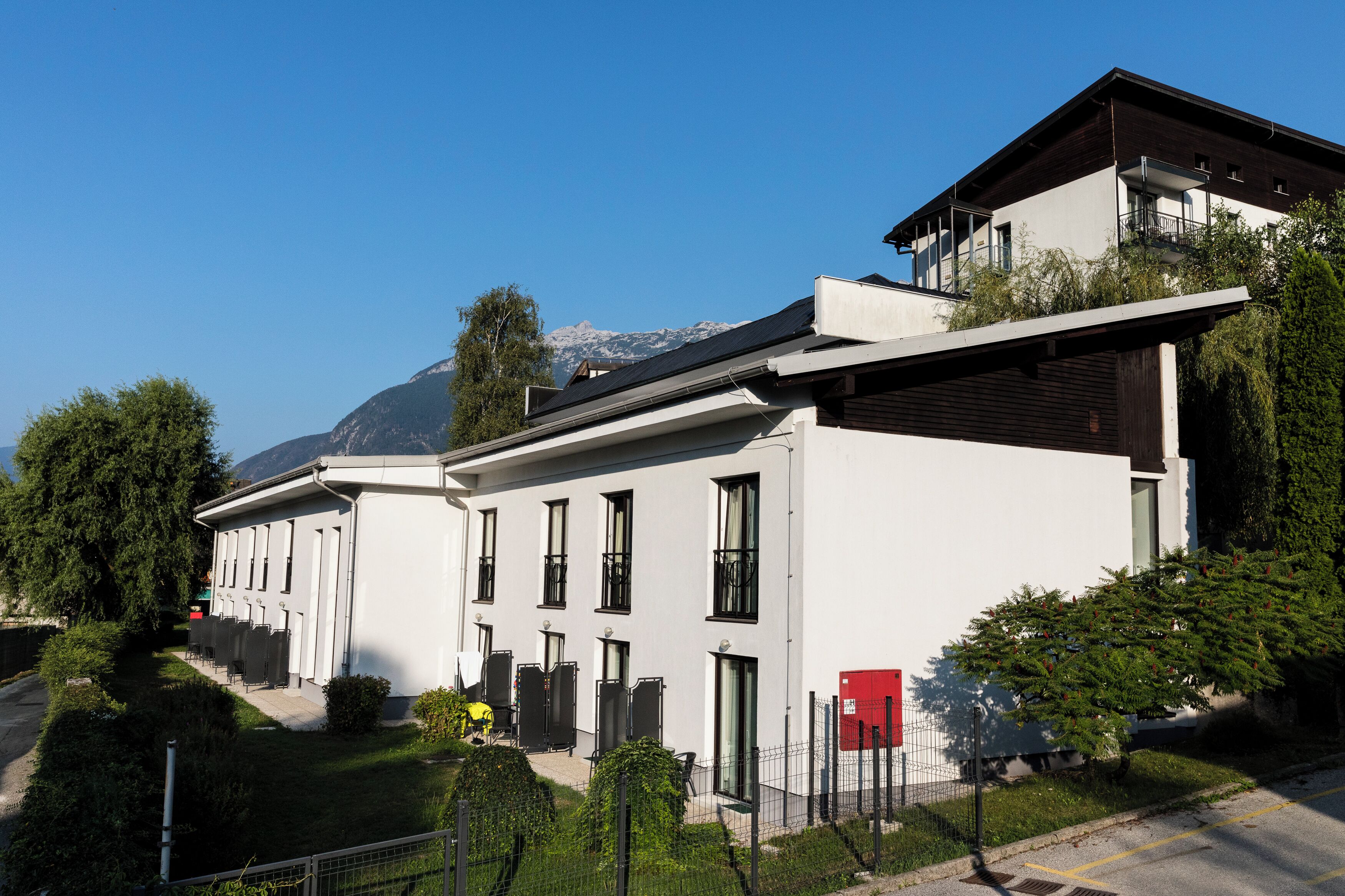 A modern building with a flat roof, large windows, and a balcony.