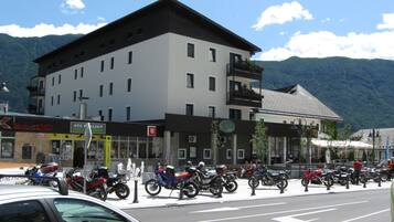 A hotel with multiple floors, a balcony on the upper level, and a mountain backdrop.