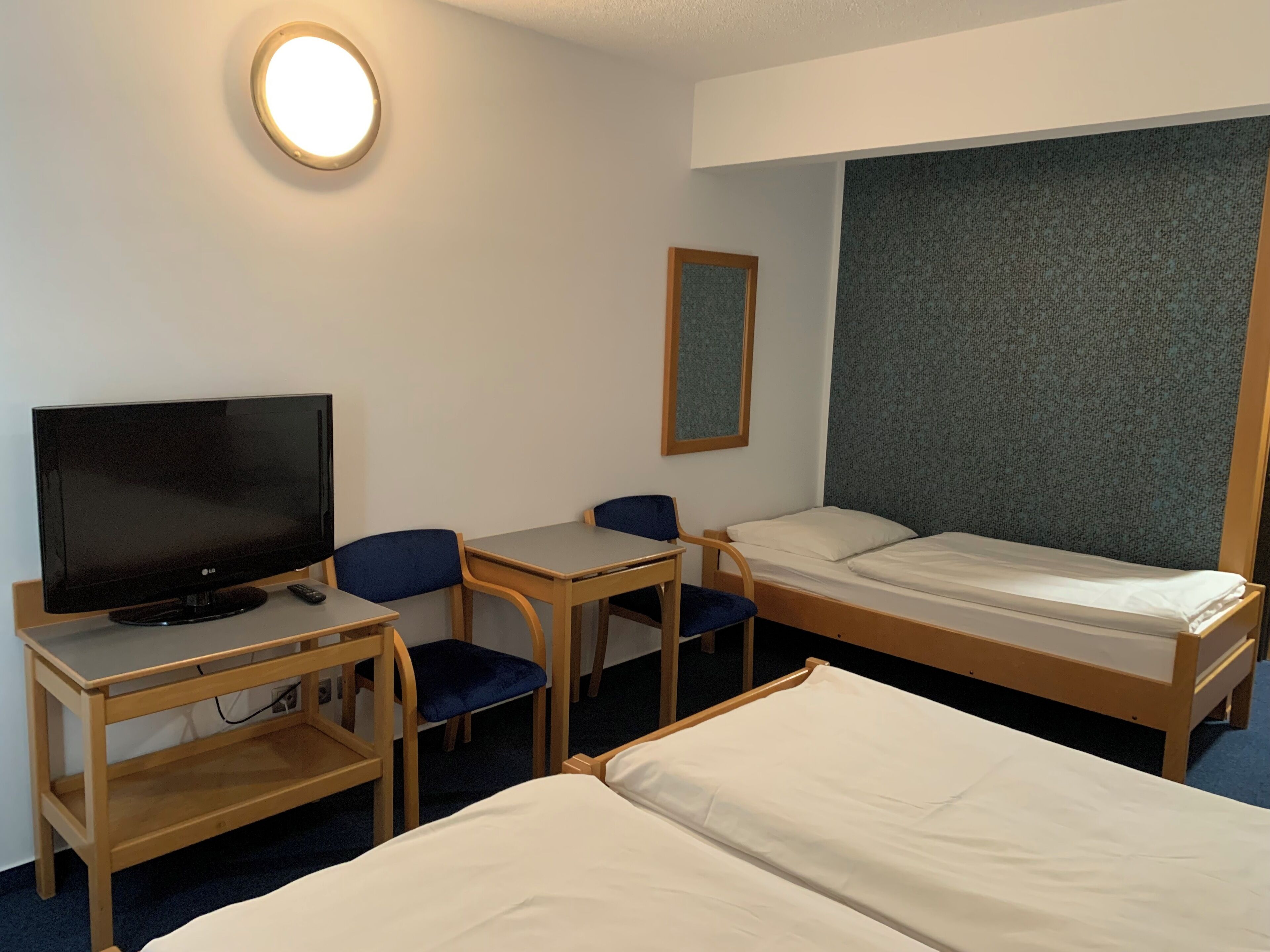 A hotel room with a bed, a desk with a TV, and a chair.