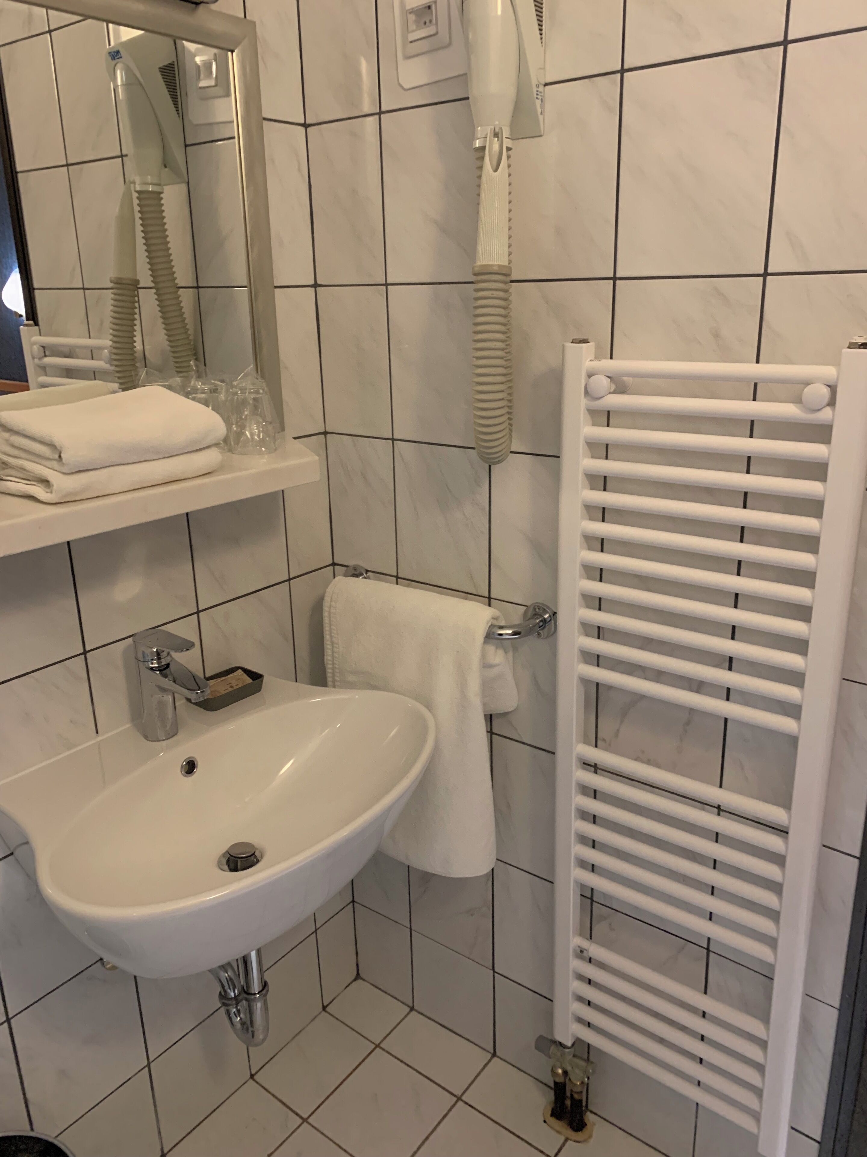 Un bagno con lavandino, specchio, portasci e un asciugamano bianco.