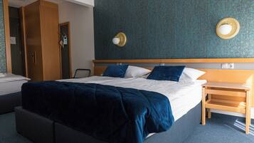 Une chambre d’hôtel avec un grand lit, une table de chevet en bois, une armoire et un miroir fixé au mur.