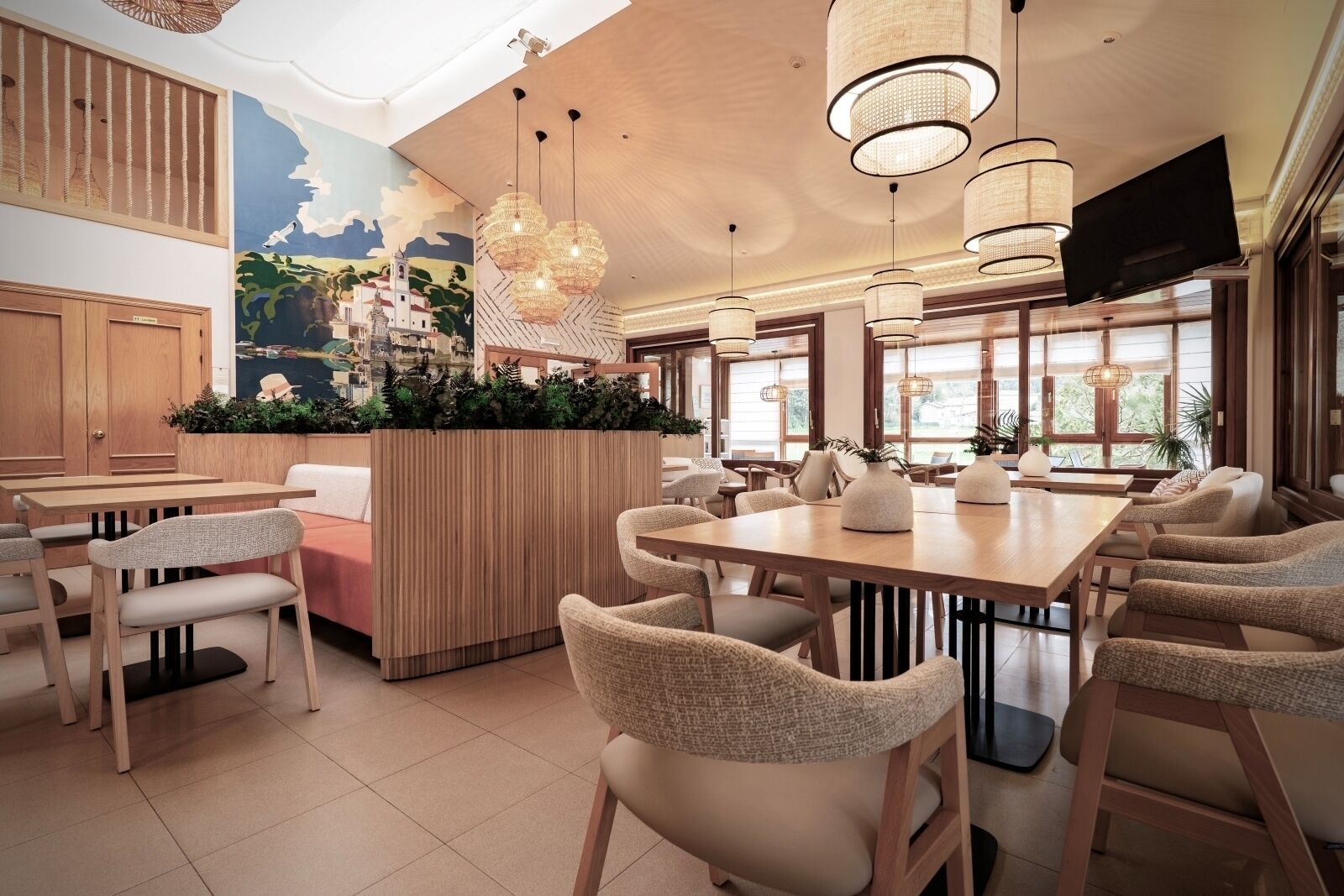 A modern restaurant with wooden furniture, hanging pendant lights, and a mural on the wall.