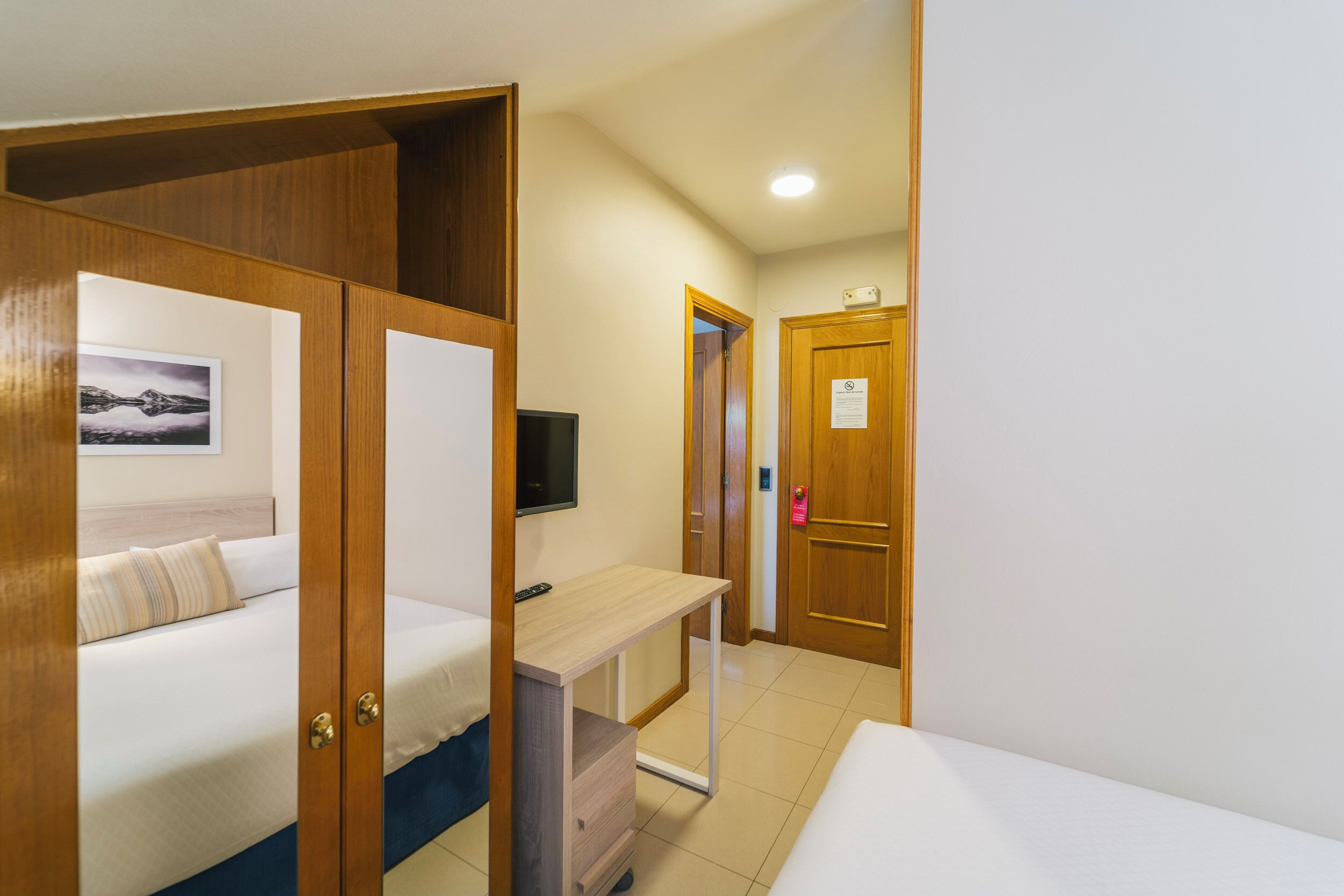 A hotel room with a bed, a desk, and a TV.