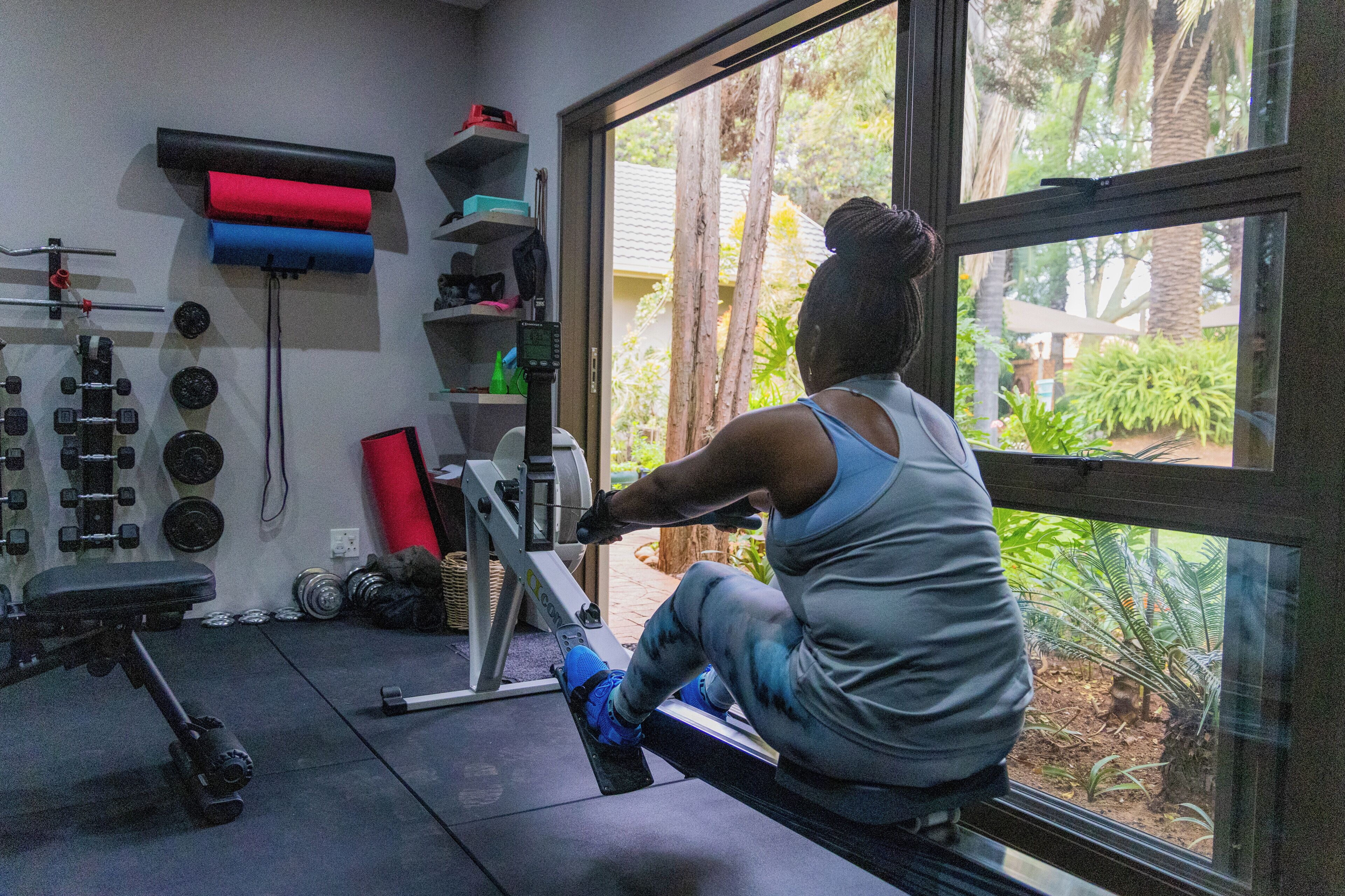 A gym with exercise equipment, a bench, and a window with a view of greenery.