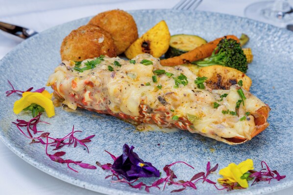 A plate with a rolled omelette, roasted potatoes, grilled vegetables, and garnishes.