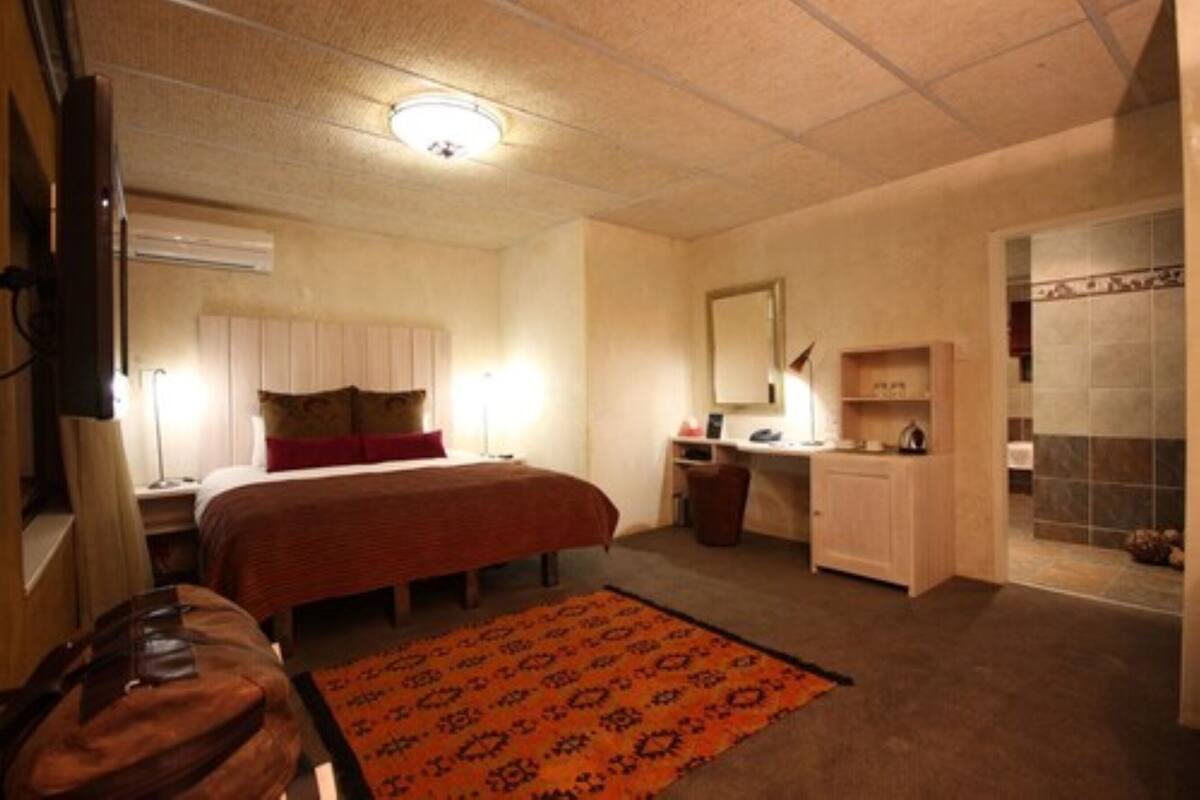 Habitación de hotel con cama, escritorio y baño con ducha.