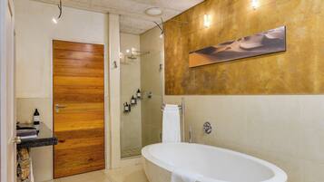 A bathroom with a wooden door, a freestanding bathtub, a glass shower enclosure, and a wall-mounted towel rack.