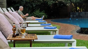 Una piscina al aire libre, sillones reclinables de piscina