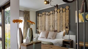 Un dormitorio con una cama grande, cabecera de madera, mesitas de noche y una ventana con cortinas.
