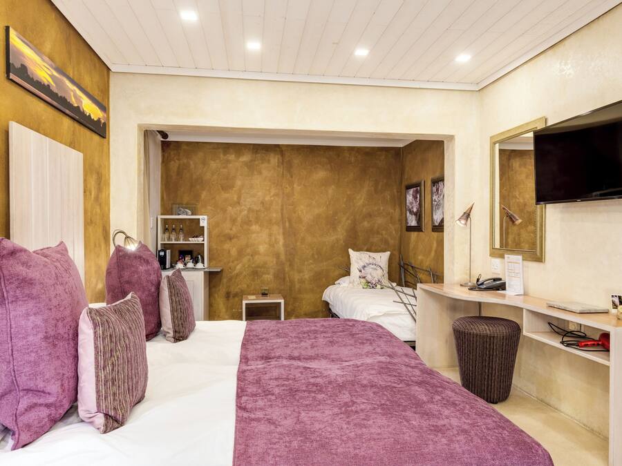 Ein Hotelzimmer mit Bett, Schreibtisch, Fernseher und einem durchgegangenen Tür erkennbaren Badezimmer.