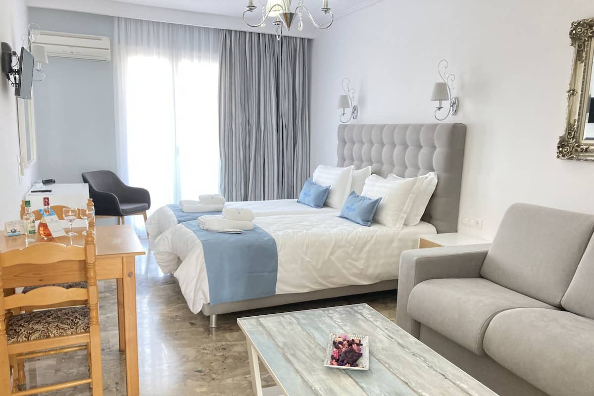 Hotellihuone, jossa on sänky, sohva, sohvapöytä, työpöytä ja tuoli.