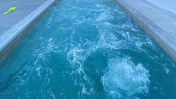 A pool with clear blue water and a yellow shovel on the edge.