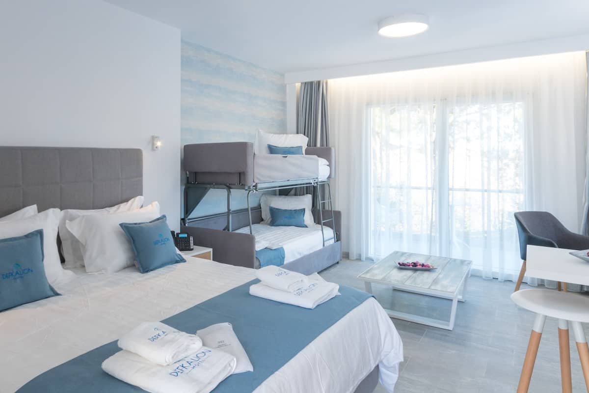 Hotellihuone, jossa on sänky, sohva, työpöytä ja tuoli.