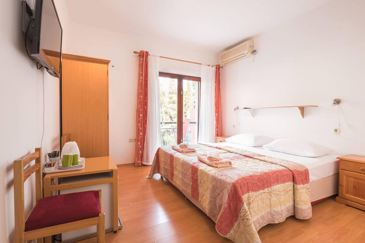 Ein Schlafzimmer mit einem Bett, einem Schreibtisch, einem Stuhl und einem Fenster mit Vorhängen.